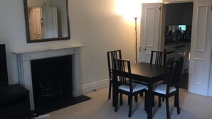 A dining area with a fireplace, a table, and four chairs. - Beautiful one bedroom in Kensington (London)