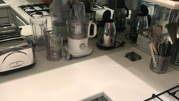 A kitchen with a built-in washer and dryer, a stove, and various appliances like a blender and coffee maker. - Beautiful one bedroom in Kensington (London)