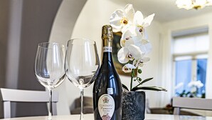 A bottle of Cormaro Prosecco Treviso DOC wine, two empty wine glasses, and a potted orchid on a table. - WINWINSTAY Residence in Heart of Old Town (Riga)