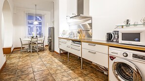 A compact kitchen with a dining area, a washing machine, and a microwave. - WINWINSTAY Residence in Heart of Old Town (Riga)