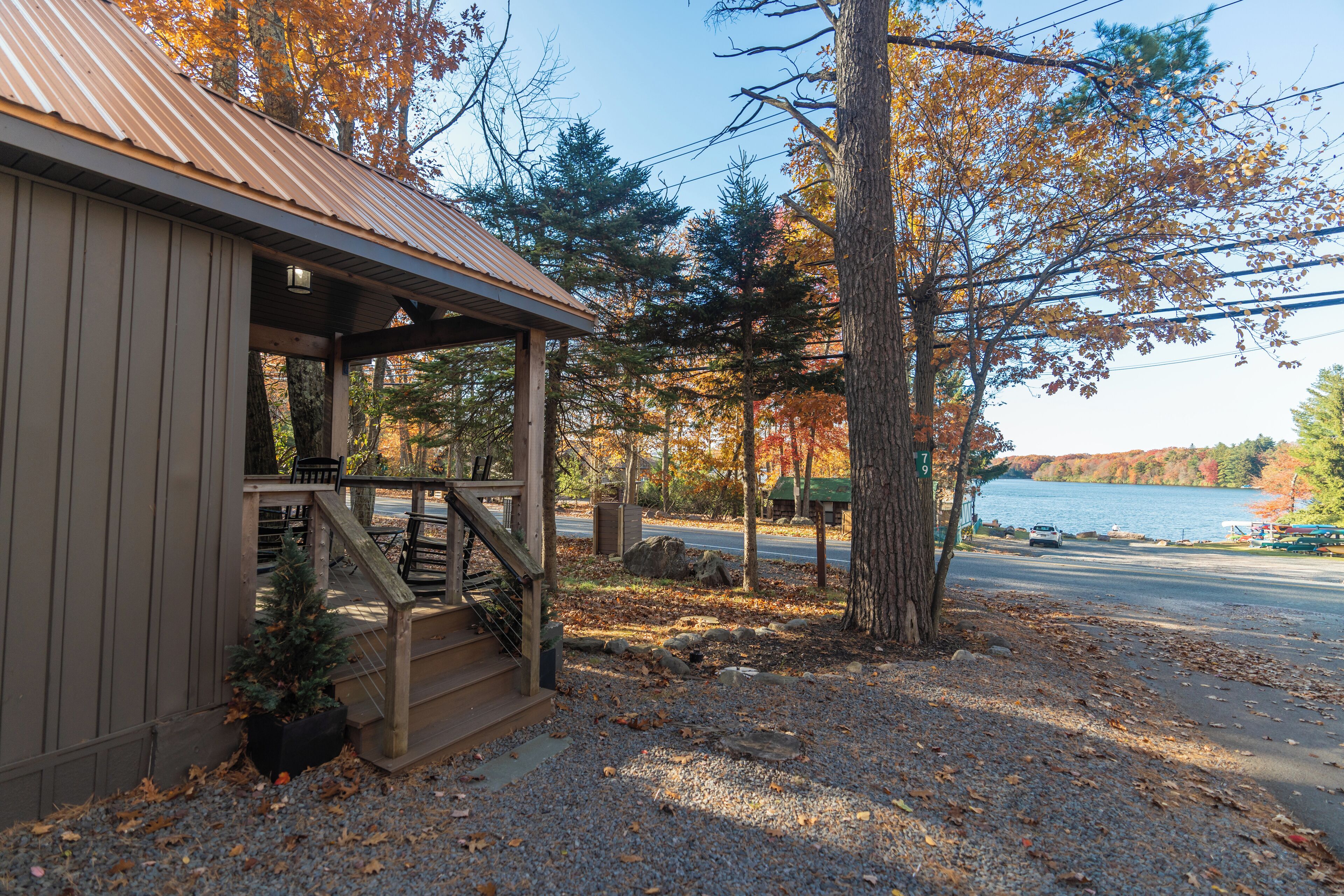 A cabin with a porch, a staircase, and a view of a lake.