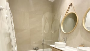 A modern bathroom with a bathtub, two sinks, and a large mirror. - Large Retro Chic Flat 100m2 in City Center - Parking (Luxembourg City)