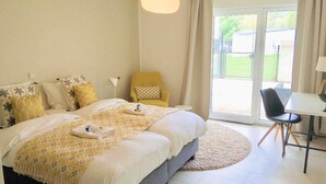 A bedroom with a bed, a chair, a table, and a view of the outdoors. - Large Retro Chic Flat 100m2 in City Center - Parking (Luxembourg City)
