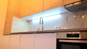 A modern kitchen with a stainless steel range hood, a digital clock, and a marble backsplash. - Large Retro Chic Flat 100m2 in City Center - Parking (Luxembourg City)