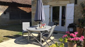 An outdoor patio with a round table, two chairs, a table umbrella, and potted plants. - Picturesque village,  2 amazing restaurants, creperie and shops a few steps away (Daglan)