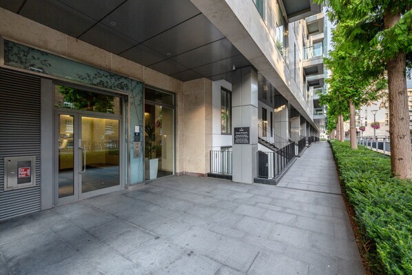 A modern building with a glass entrance, a staircase, and a well-maintained sidewalk.