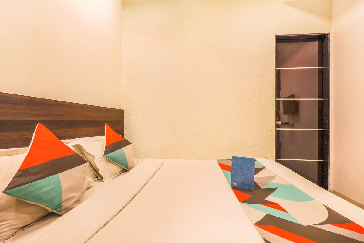 Una habitación de hotel con una cama, almohadas y una puerta.