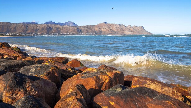 A rocky shoreline with waves crashing onto the rocks. - SeaScape Condo (Cape Town)