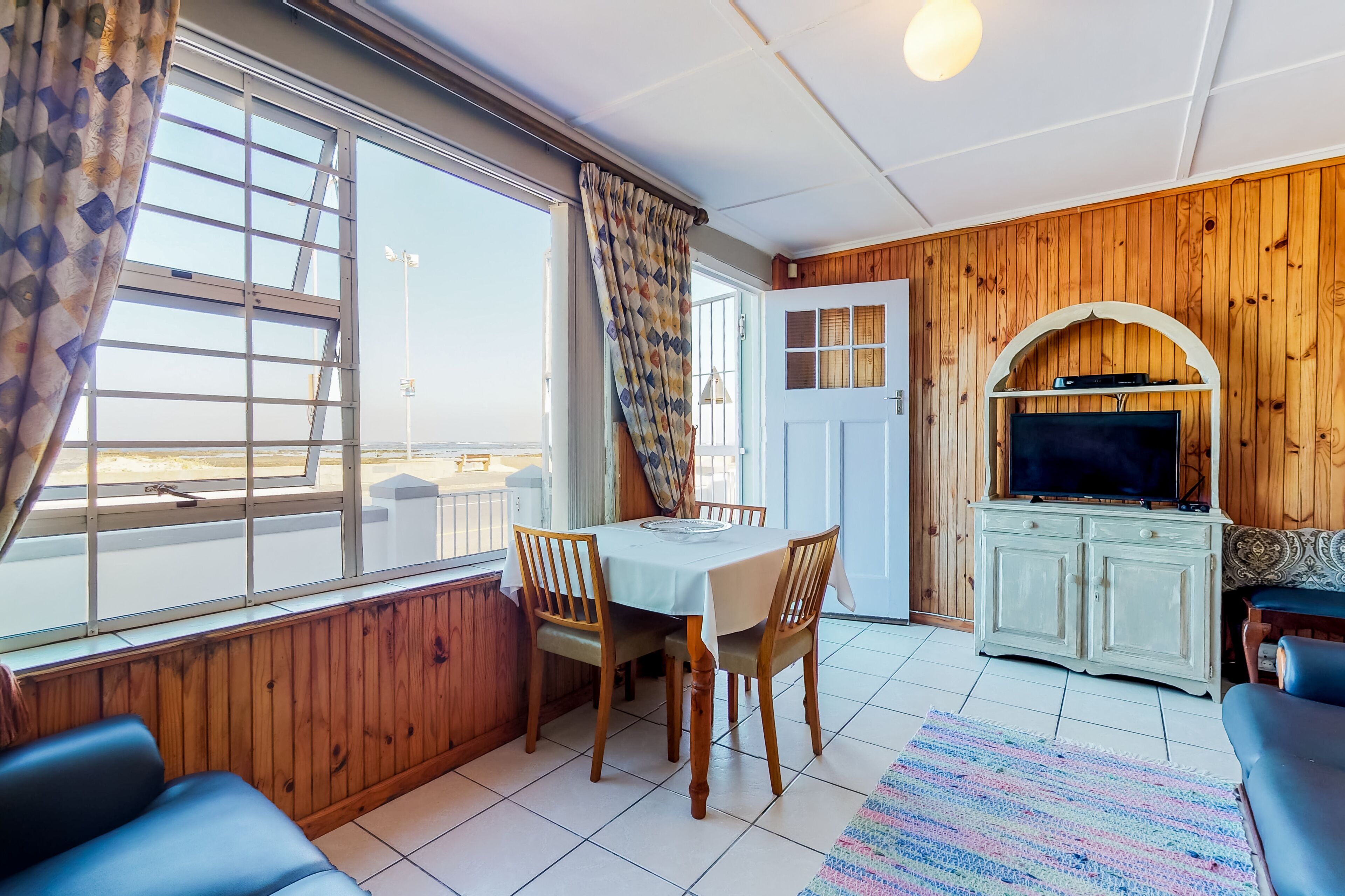 A room with a dining table, chairs, a TV, and a sofa.
