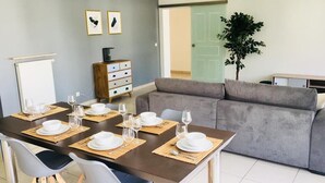 Un comedor con una mesa dispuesta para seis comensales, un sofá gris, un armario de madera y una pizarra en la pared.