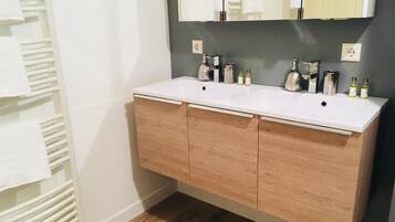 Une salle de bain avec un lavabo blanc, deux miroirs et un meuble en bois.