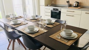 Comedor con una mesa de madera oscura dispuesta para seis personas, rodeada de sillas negras.