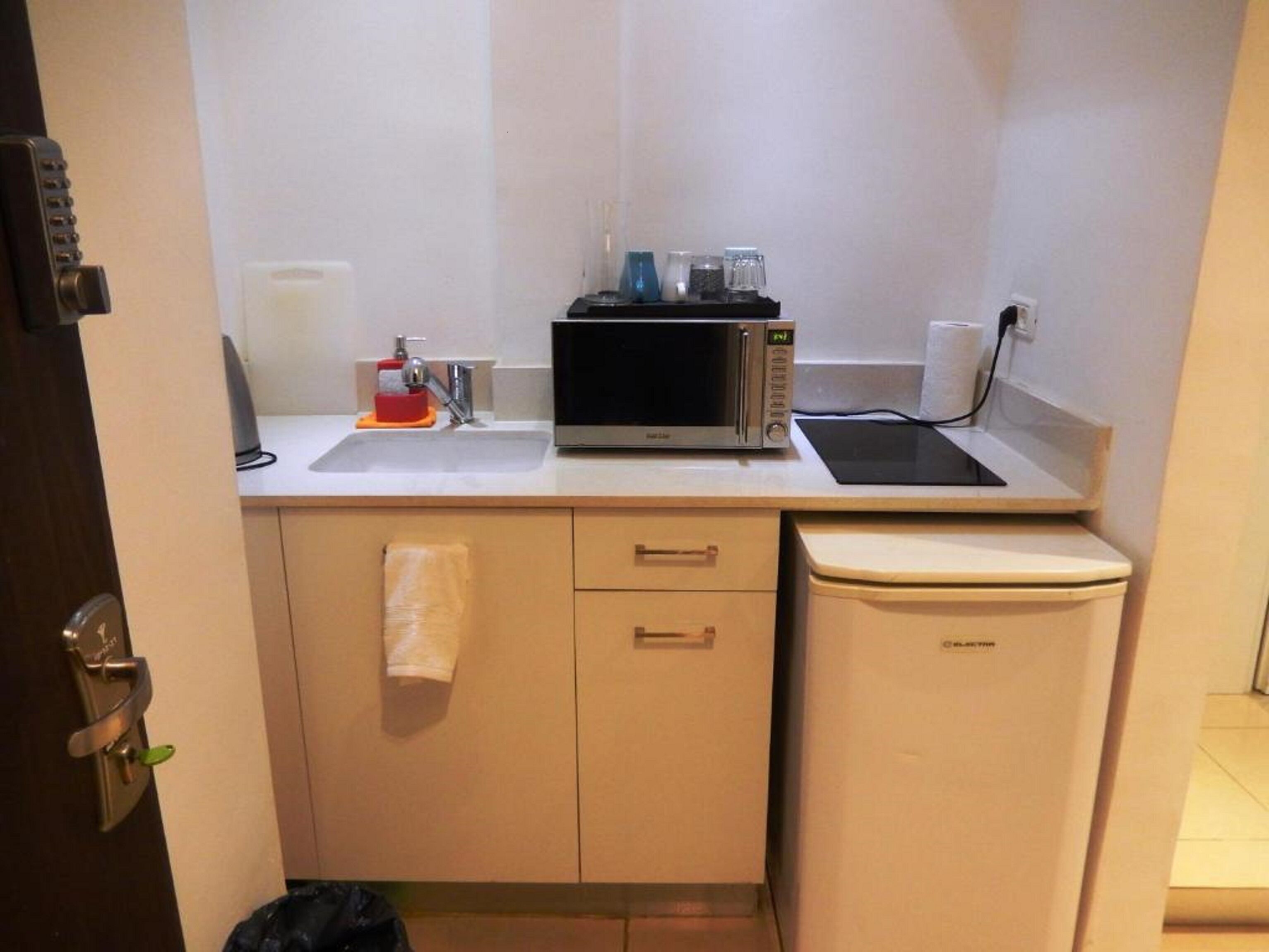 A compact kitchenette with a microwave, a small sink, and a refrigerator.