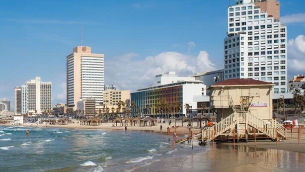 A beachfront hotel with multiple floors, a beach in the foreground, and a clear sky. - Gorgeous Studio On Hilton Beach (Tel Aviv)