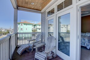 Un balcone con due poltrone Adirondack, un soffitto in legno e vista sulle case vicine.
