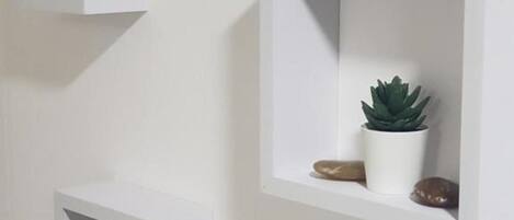 Three white, wall-mounted shelves with plants and decorative items.