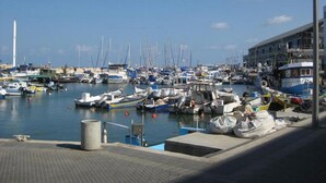 A marina with numerous boats docked, a clear sky, and a building with a balcony on the right. - Large Beautiful Studio in Old Jaffa (Tel Aviv)