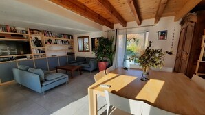 A modern living room with a wooden ceiling, a sofa, a coffee table, a dining table with chairs, a TV, and a bookshelf. - Welcoming house, exceptional view, in the hamlet of Cezas. (Sumène)