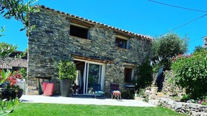 A stone building with a patio area, a lawn, and a stone wall. - Welcoming house, exceptional view, in the hamlet of Cezas. (Sumène)