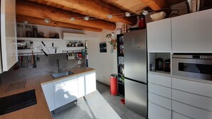 A modern kitchen with wooden beams, white cabinetry, a stainless steel refrigerator, and a built-in oven. - Welcoming house, exceptional view, in the hamlet of Cezas. (Sumène)