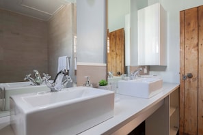 A modern bathroom with two sinks, a large mirror, and wooden accents.