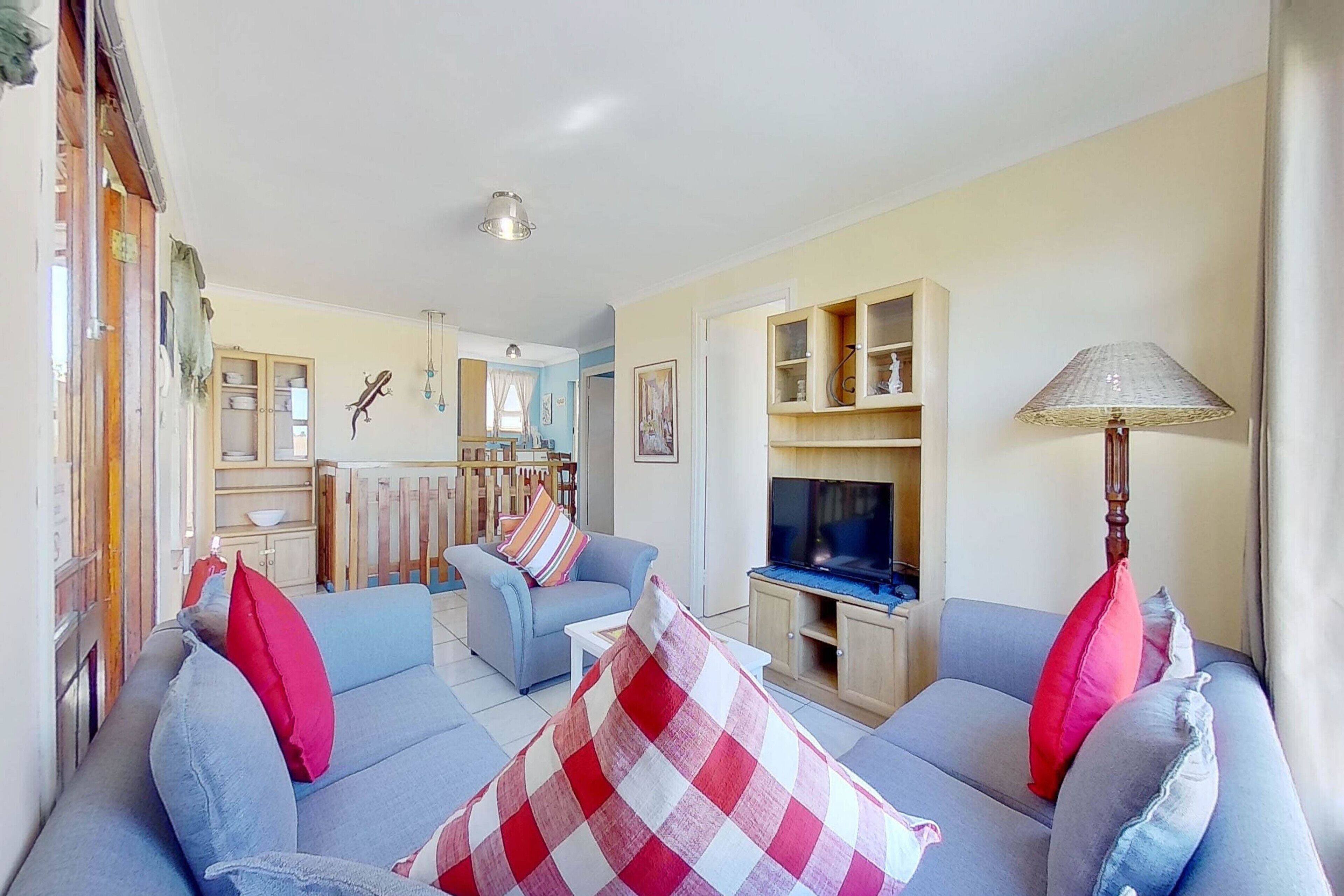A living room with a sofa set, a television, and a lamp.