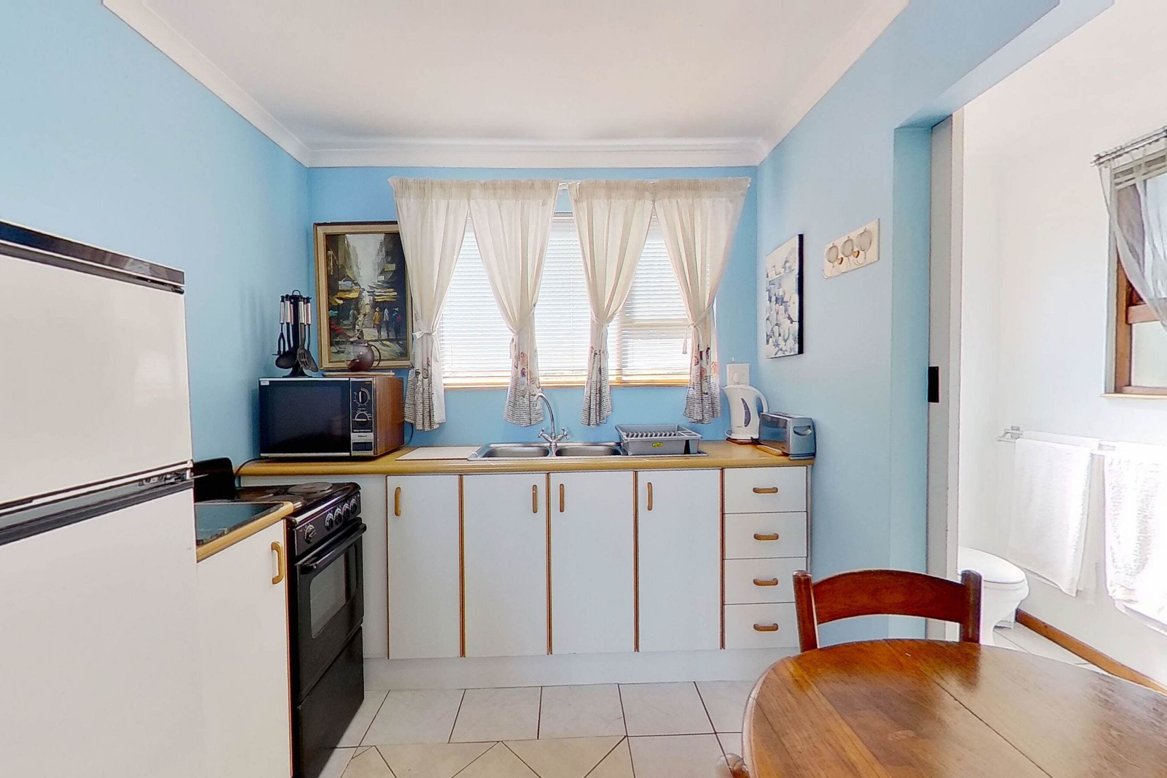 A compact kitchen with white cabinets, a wooden table, and a sink.