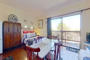 A room with a bed, a dining table, a fan, and a balcony with a view. - Akkedissie 2 (Cape Town)