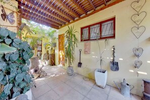 A covered patio area with potted plants, a wooden ceiling, and a wall with heart-shaped decorations. - Akkedissie 2 (Cape Town)