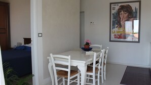 Un comedor con una mesa y sillas blancas, una planta en maceta y un cartel en la pared.