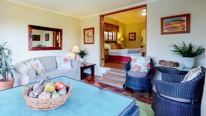 A living room with a sofa, chairs, a coffee table with fruit, and a staircase leading to a bedroom. - Somerset Oaks (Cape Town)
