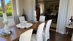 A dining area with a wooden table, white chairs, and a vase of flowers.