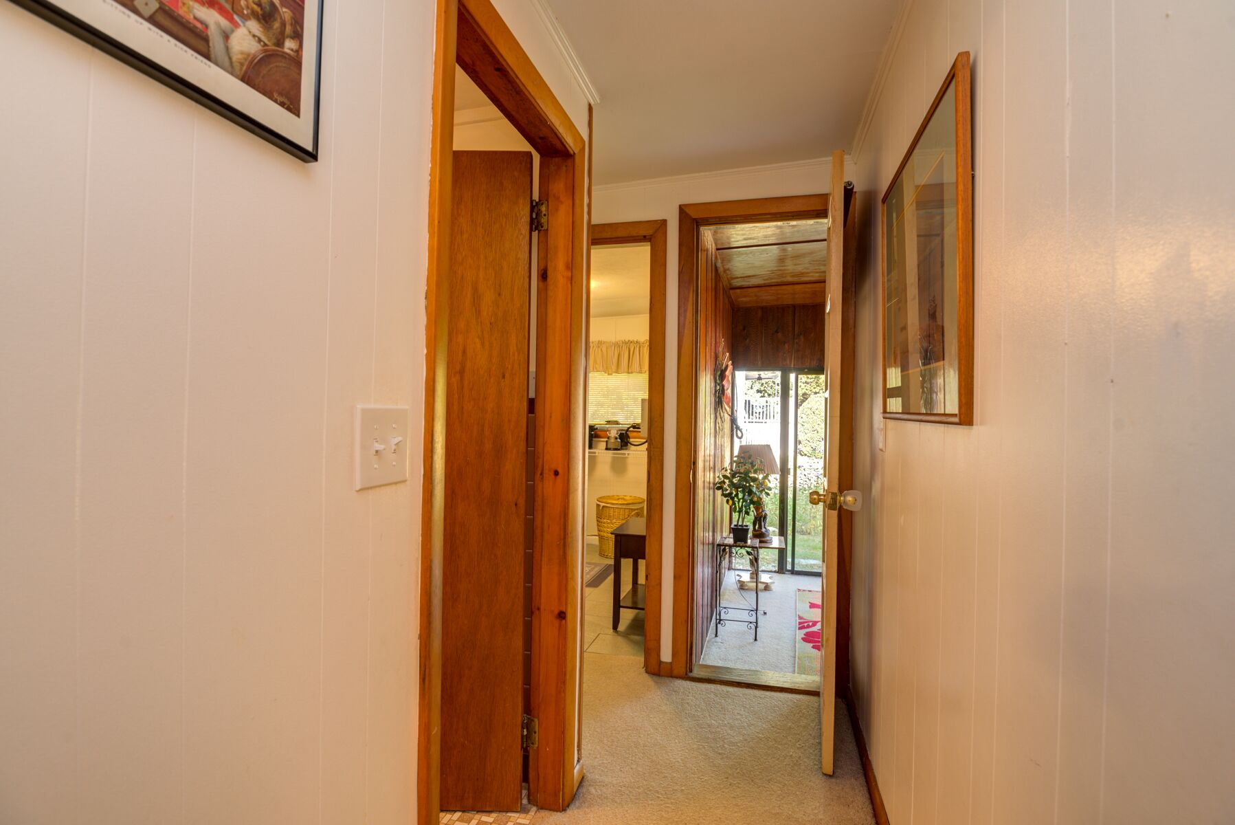 A hallway with wooden doors leading to a kitchen and a balcony.