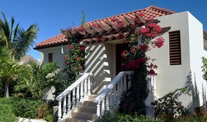 A two-story house with a red-tiled roof, white exterior walls, and a white staircase with balusters.