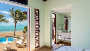 Habitación con vista a la playa, una piscina y un baño con lavabo y espejo.