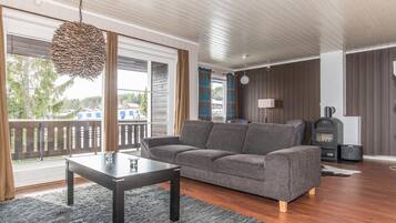 Een woonkamer met een bank, een salontafel, een open haard en uitzicht op buiten.