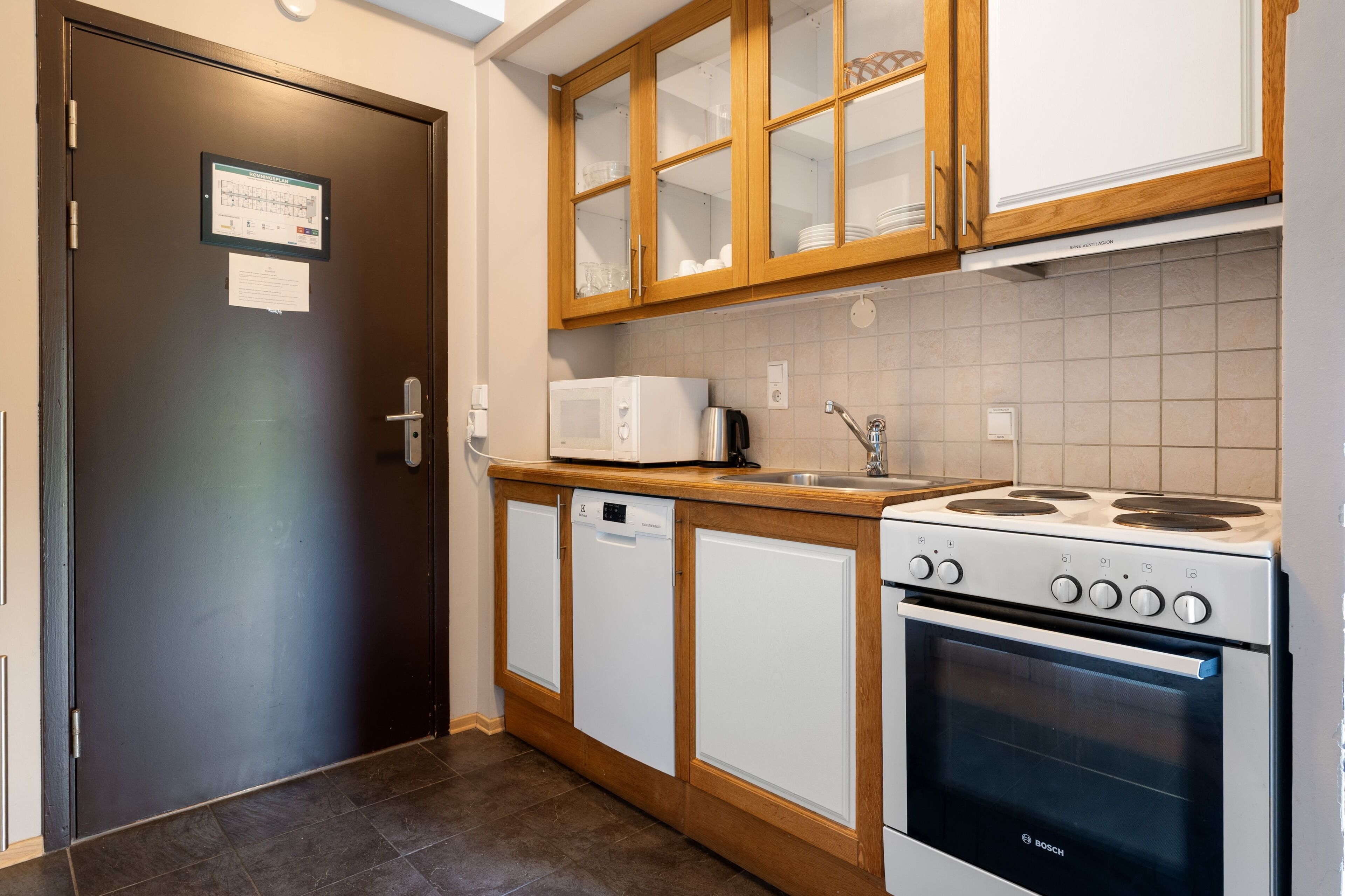 Una cucina con mobili in legno, un forno a microonde, una lavastoviglie e un forno Bosch.