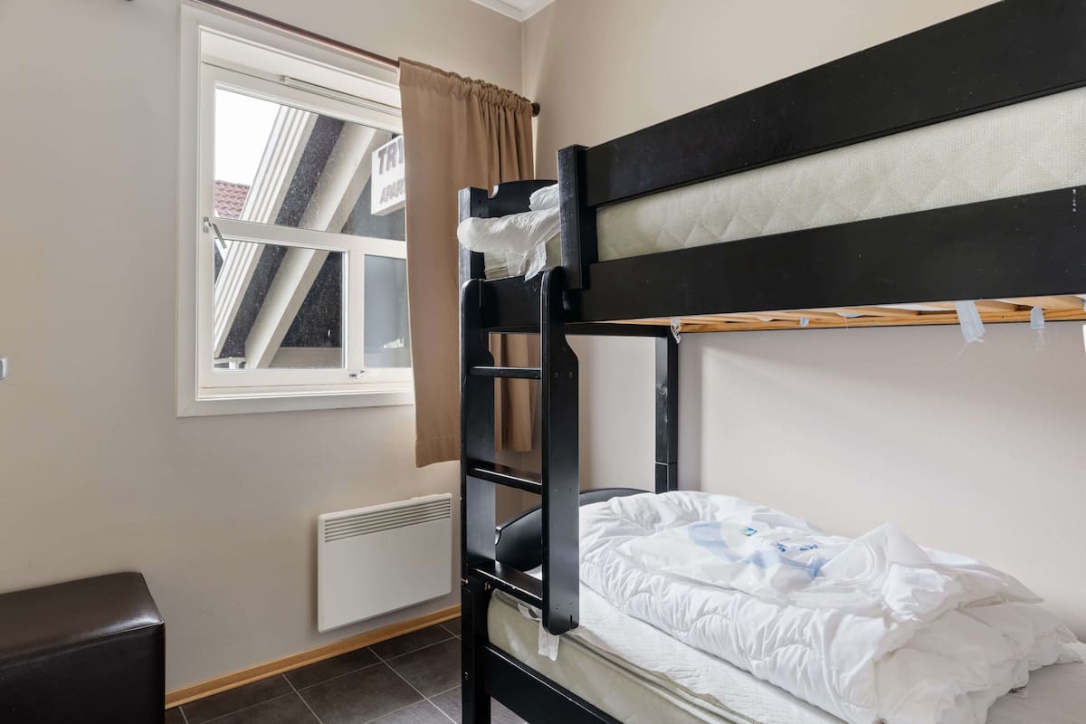 A bunk bed with a window, a radiator, and a small table.