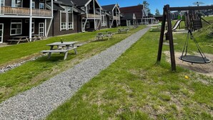 A row of wooden cabins with a gravel path and picnic tables. - Trysilfjell Apartment Hotel (Trysil)