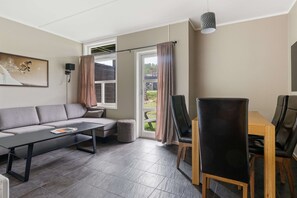 A modern living room with a sofa, coffee table, and dining table with chairs.