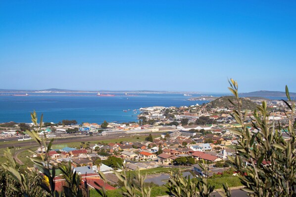 A coastal town with a mix of residential and commercial buildings, a prominent hill, and a clear view of the sea.
