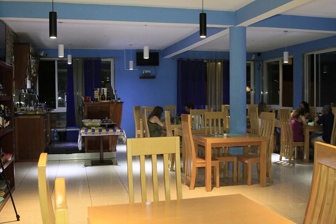 A restaurant with wooden tables and chairs, a bar area, and a television mounted on the wall.