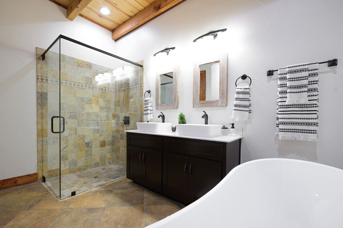 Un baño moderno con cabina de ducha de vidrio, una bañera independiente, un lavamanos doble y un espejo grande.