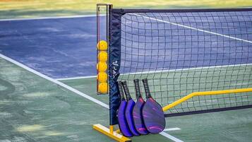 Un court de tennis avec un filet, une machine à lancer des balles et des raquettes.
