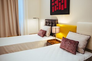 A hotel room with two beds, a modern lamp, and a large abstract painting on the wall.