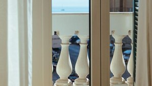 A view through a glass door with a balcony, featuring white balustrades and a glimpse of a building with balconies in the background. - Casa Vittoria Napoli - Santa Lucia (Naples)