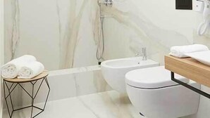 A modern bathroom with a marble wall, a freestanding sink, a toilet, and a towel rack. - Casa Vittoria Napoli - Santa Lucia (Naples)