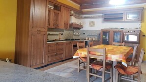 Une cuisine avec des meubles de rangement en bois, une table à manger avec des chaises et une cuisinière.