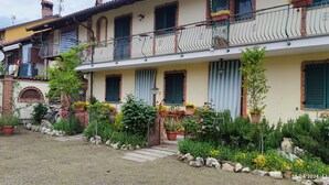 Un immeuble de deux étages doté d’un balcon, de plantes en pot et d’un jardin.