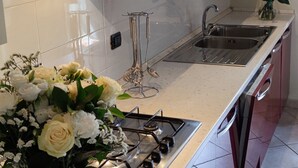 Une cuisine moderne équipée d’une cuisinière à gaz, d’un évier en acier inoxydable et de meubles blancs.